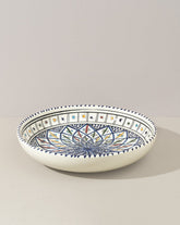 A ceramic decorative large bowl with hand-painted patterns in blue, green, and other colors on a white background, displayed against a neutral backdrop.