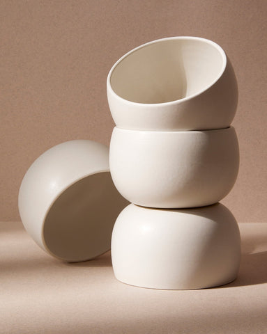 A stack of three white stoneware soup bowls of different sizes on a neutral background.