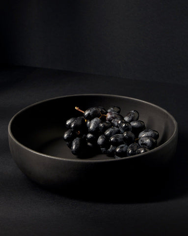 A beige Stoneware Shallow Serving Bowl with a capacity of 60 oz, displayed against a neutral background with a small amount of food items like pasta or noodles in it to showcase its size and shape.