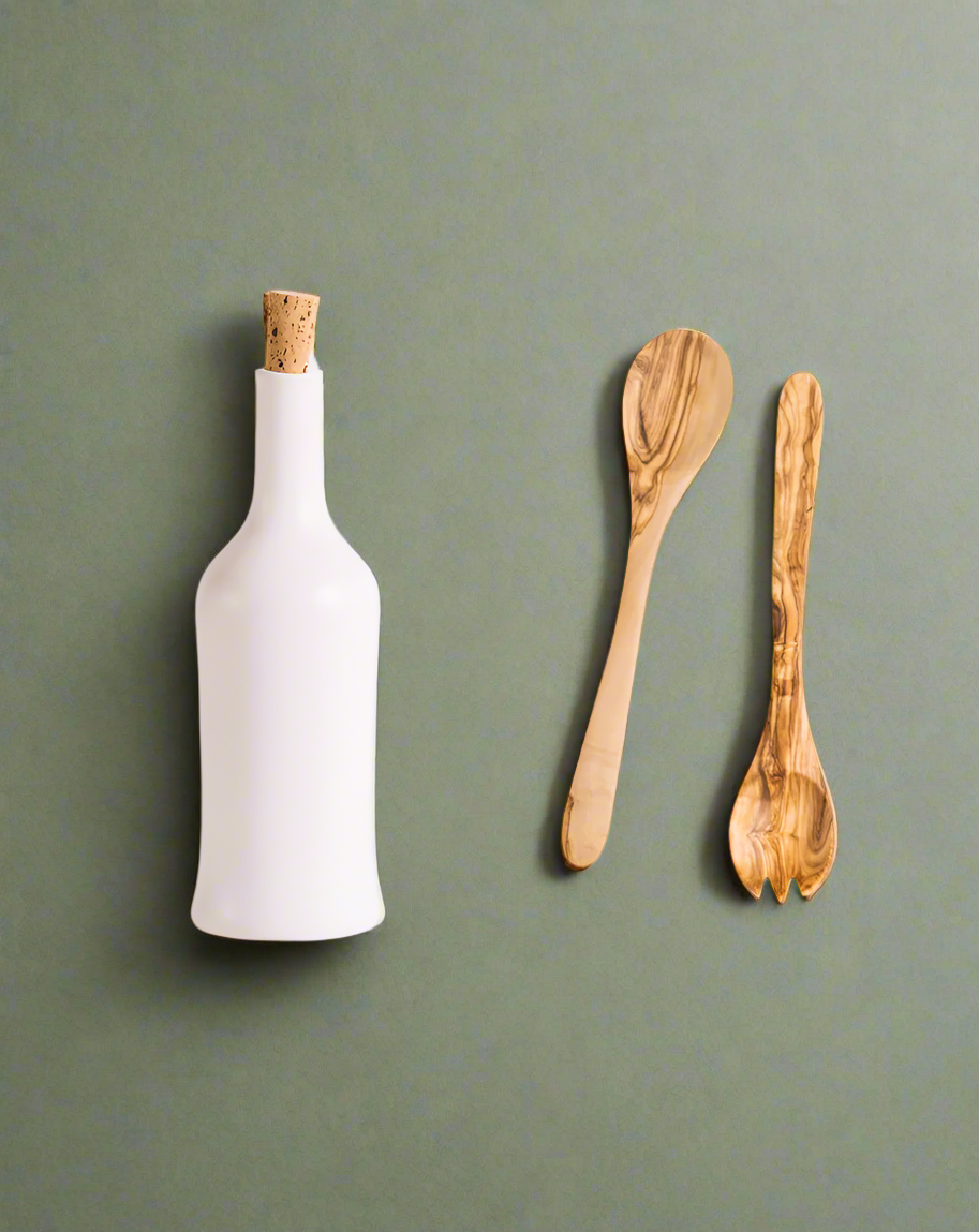A handcrafted olive wood salad server set accompanied by a stoneware bottle, both displayed against a neutral background.