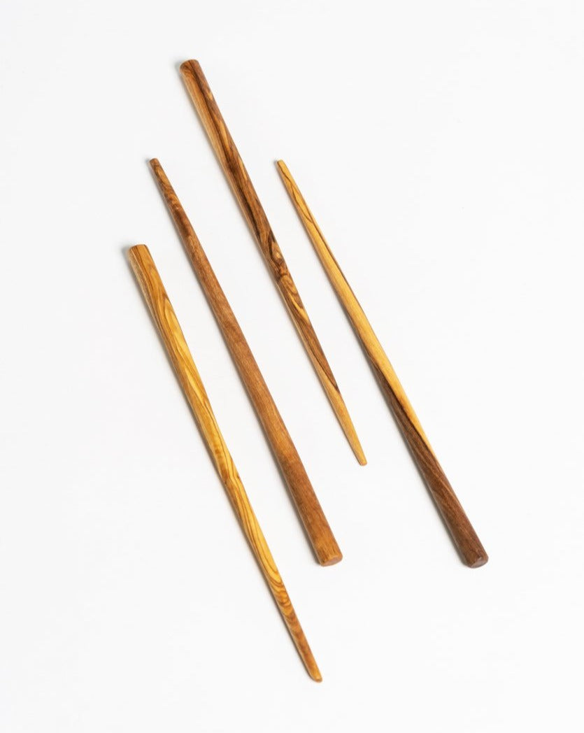 Four wooden chopsticks neatly arranged on a white background, showcasing their smooth finish and natural wood grain.
