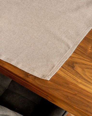 A Taupe cotton placemat is laid out on a wooden table.