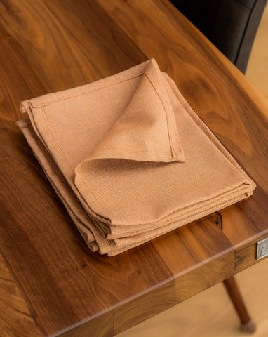 A folded Copper cotton napkin on a wooden dining table