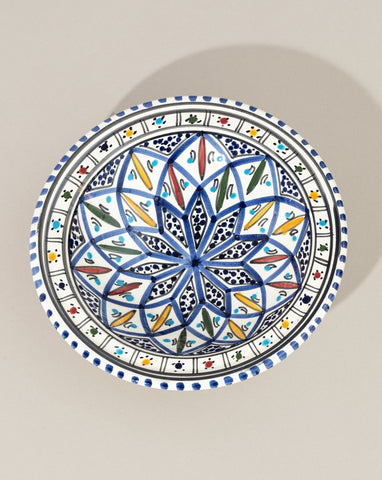 A ceramic decorative plate with a hand-painted geometric pattern predominantly in blue and white colors.