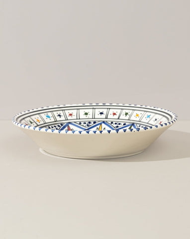 A ceramic decorative plate with a hand-painted geometric pattern predominantly in blue and white colors.