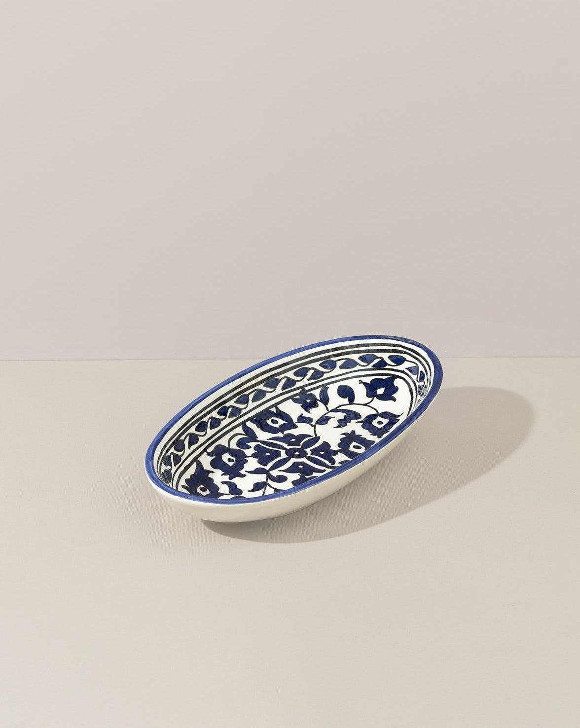 A single oval ceramic plate with a hand-painted blue and white floral design, displayed on a white background, highlighting its delicate craftsmanship.