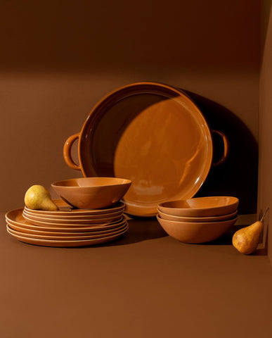 A set of white stoneware dinnerware including flat round dinner plates, flat round salad plates, organic-shaped soup bowls, and a large plate with handles.