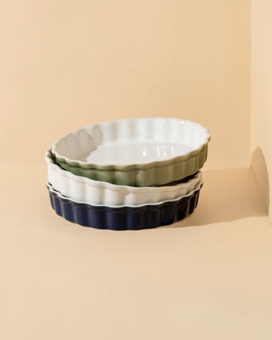A ceramic pie dish with wavy sidewalls in shades of blue and white, displayed against a neutral background.