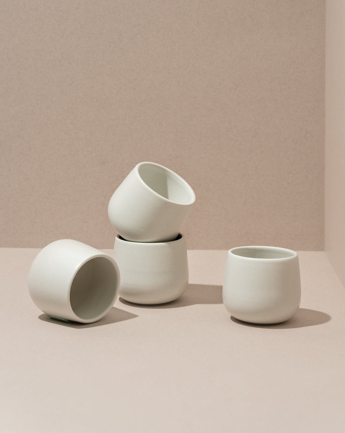 Three stoneware coffee cups in different sizes with a matte finish, displayed against a neutral background.