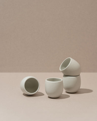 Four stoneware creamer cups in a matte finish, with one cup partially filled with a creamer, displayed against a neutral background.