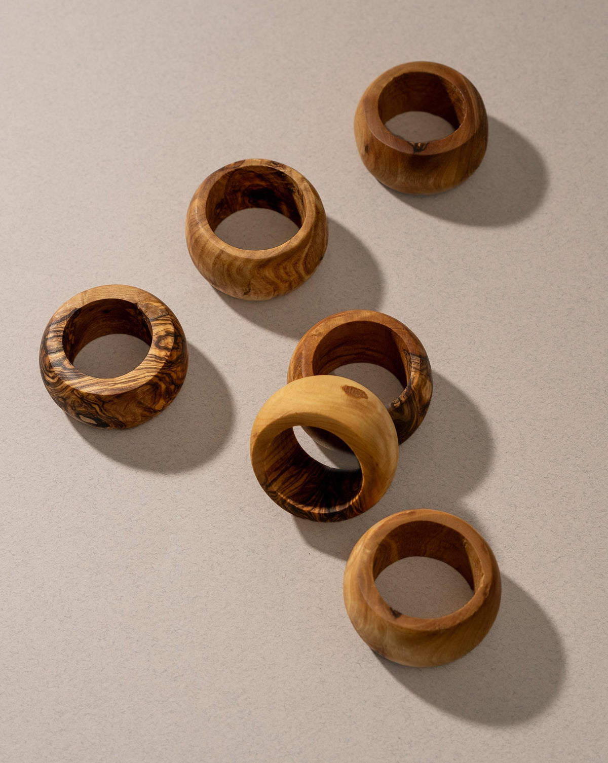 A set of olive wood napkin rings displayed on a neutral surface.