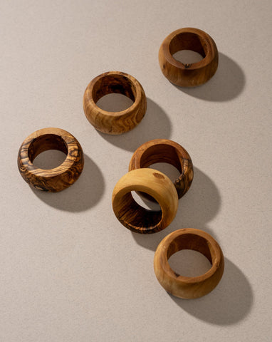 A set of olive wood napkin rings displayed on a neutral surface.