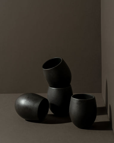 A set of four stoneware espresso tumblers in a neutral color, stacked in a pyramid shape against a neutral background.