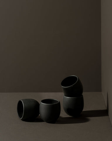 Four stoneware creamer cups in a matte finish, with one cup partially filled with a creamer, displayed against a neutral background.