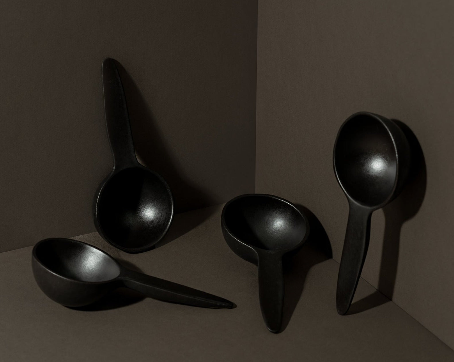 A set of four stoneware bowl with a spoon shape, displayed against a dark background.