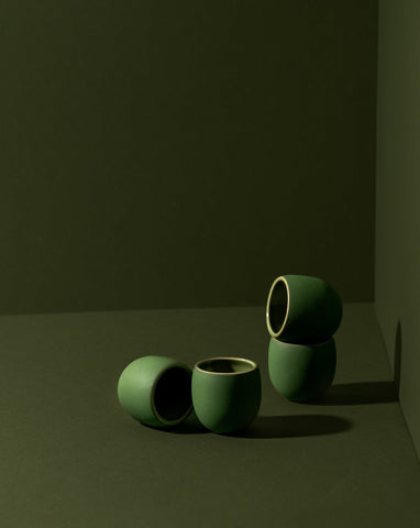 Four stoneware creamer cups in a matte finish, with one cup partially filled with a creamer, displayed against a neutral background.