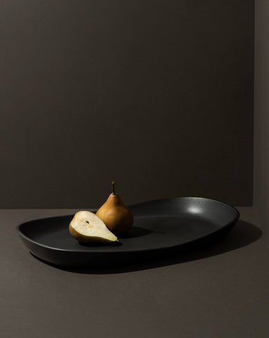Mini stoneware serving platter with a selection of pastries and blackberries on a kitchen countertop.