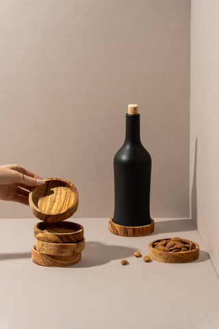 Stacked olive wood bowls, one with a wine bottle and another with walnuts, displayed against a warm background