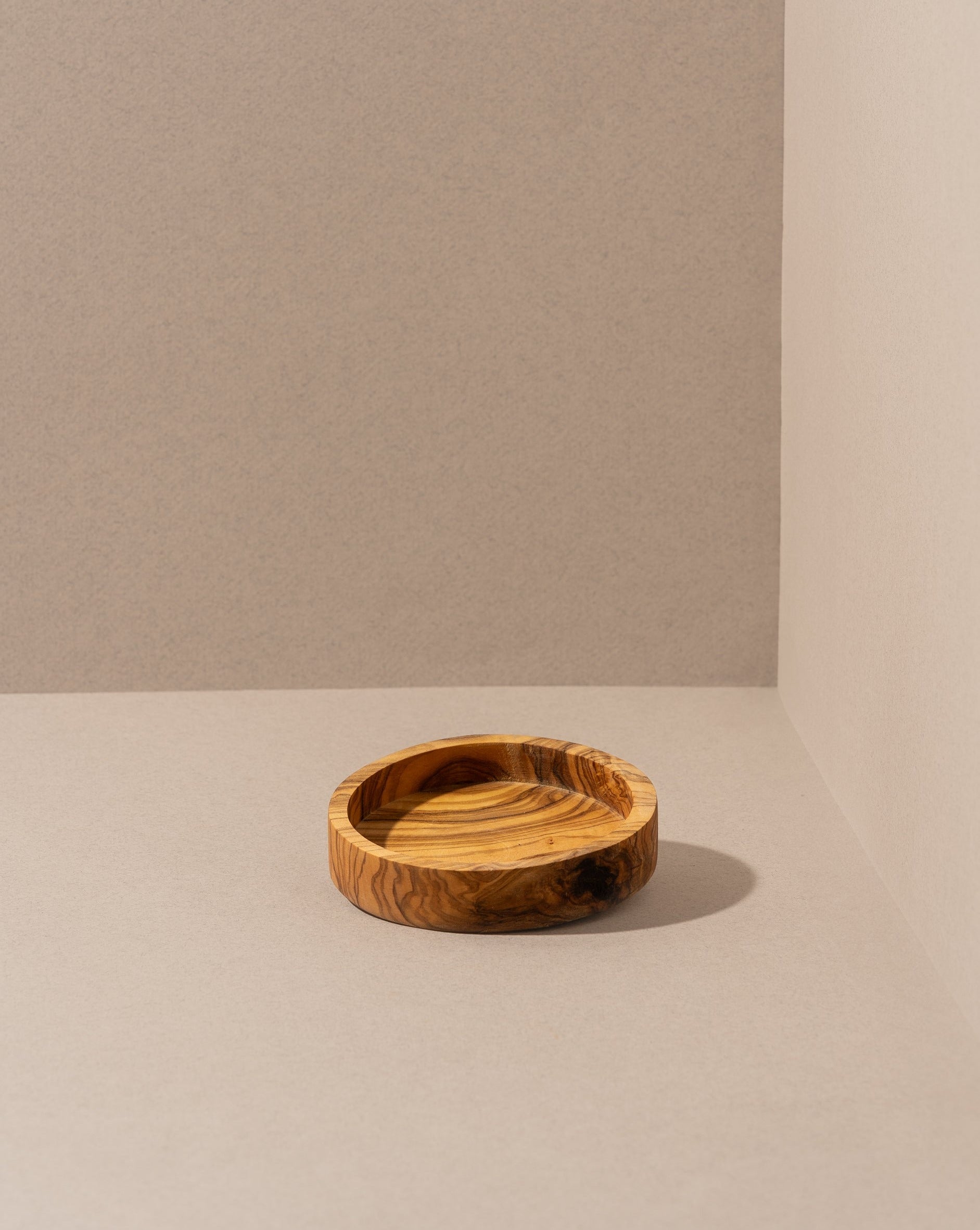 olive wood bowl with rich grain pattern, displayed against a dark background.