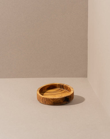 olive wood bowl with rich grain pattern, displayed against a dark background.