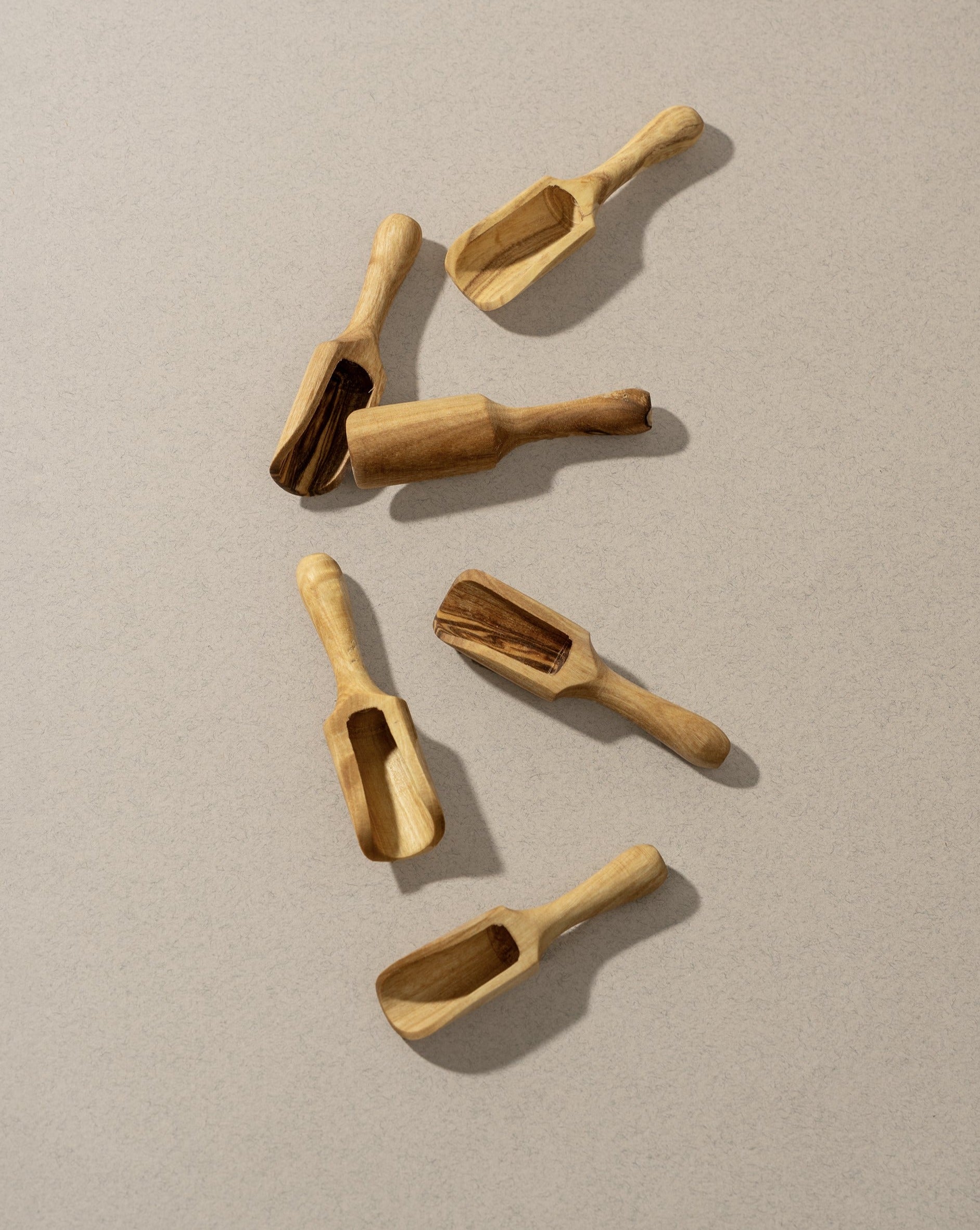 A collection of wooden scoops of various sizes, displayed against a neutral background.