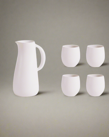 A stoneware jug in green color accompanied by four matching cups, displayed against a neutral background.