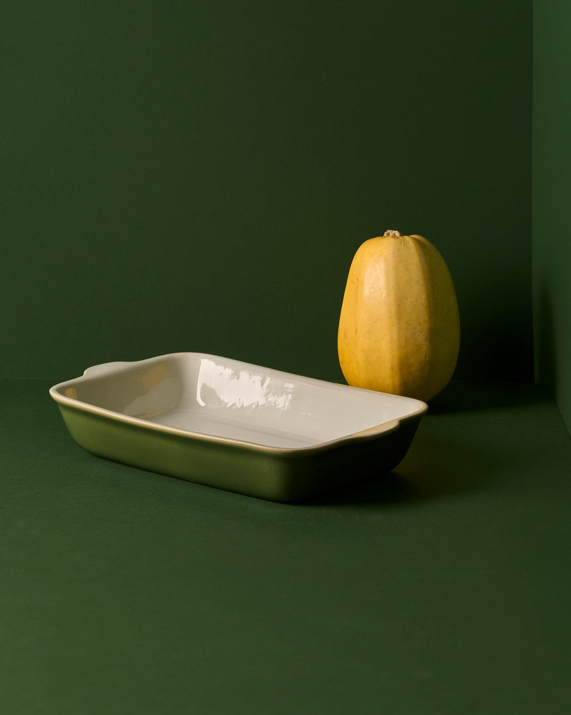 A stack of rectangular stoneware baking dishes in beige, blue, and green colors.