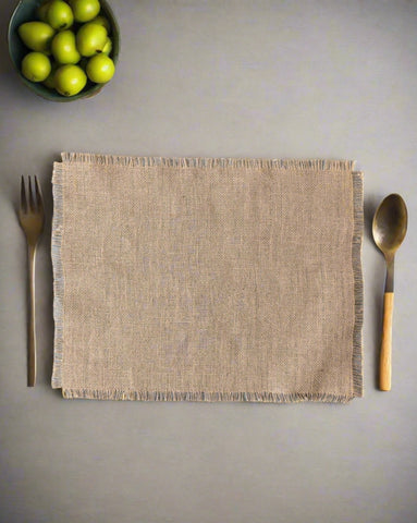 A beige burlap placemat on a gray surface with a fork on the left side and a spoon on the right side, both with wooden handles.