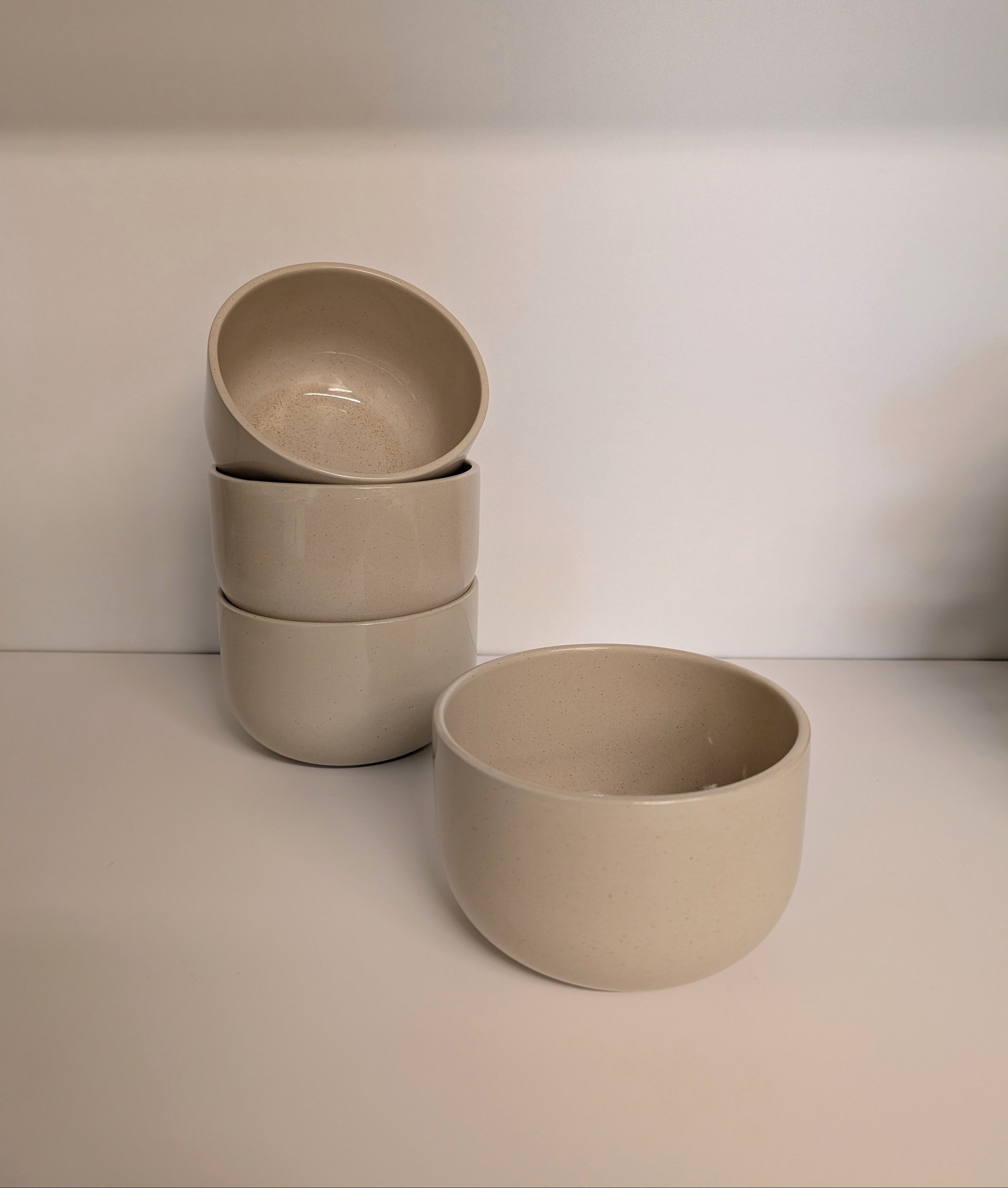 Set of three beige ceramic bowls on a white surface with a white background