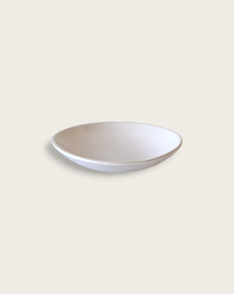 Two stoneware dessert plates with a matte finish, one containing some food residue, placed on a textured surface with a fork and spoon to the side.