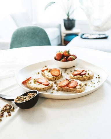 A stoneware serving platter with organic forms and a matte finish, presented on a table with food items arranged on top.