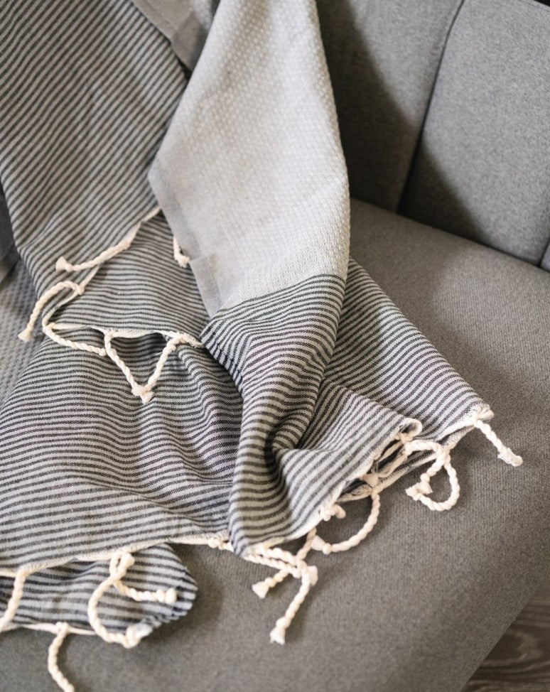 A fouta towel laid flat on a sofa, showcasing its texture and pattern in a relaxed, indoor setting.