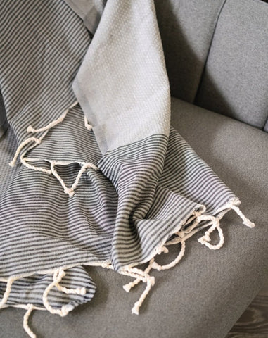 A fouta towel laid flat on a sofa, showcasing its texture and pattern in a relaxed, indoor setting.