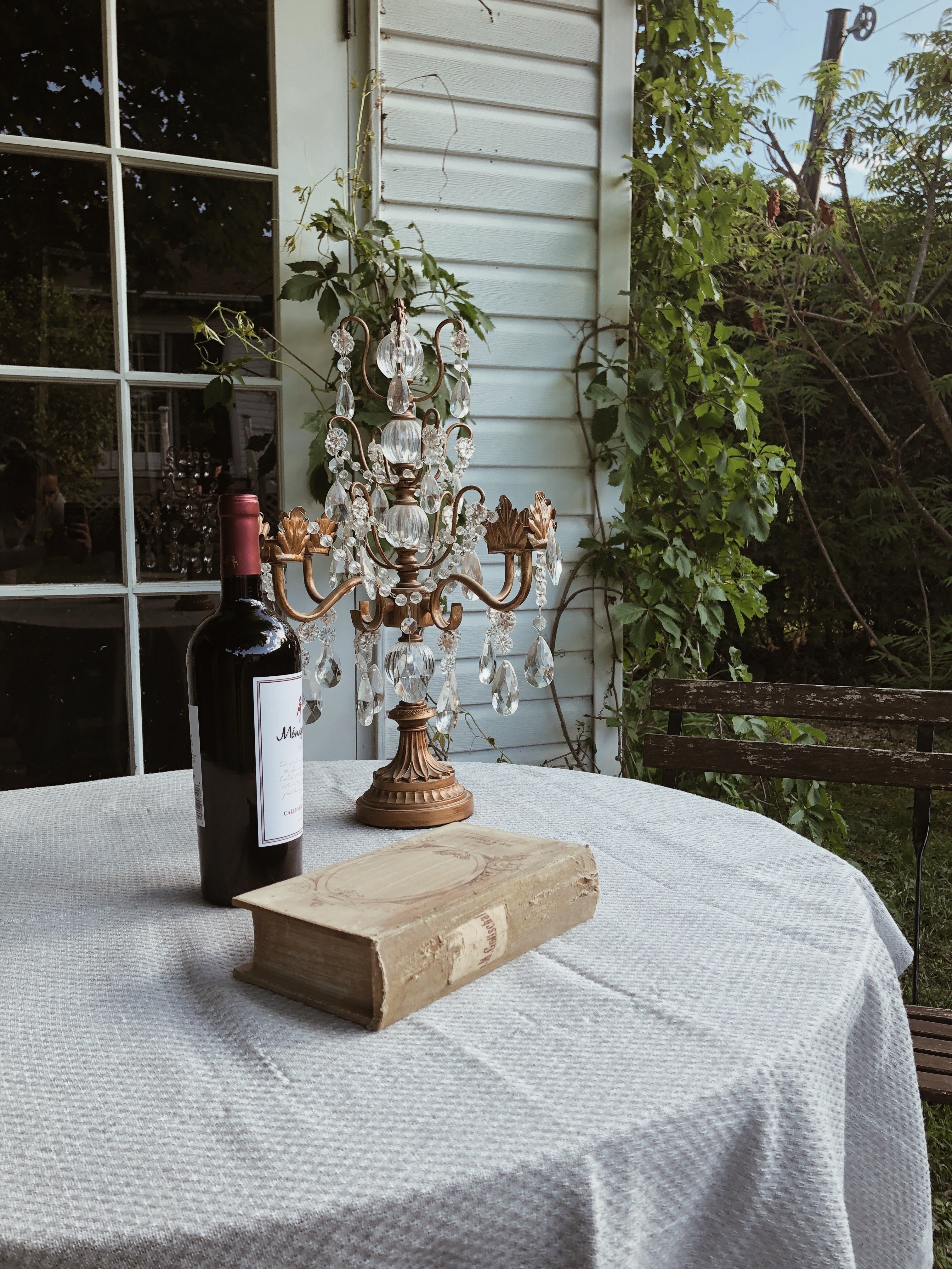 A fouta towel styled as part of a table setup, with a book, a glass of wine, and a decorative chandelier overhead, creating an elegant and cozy ambiance.
